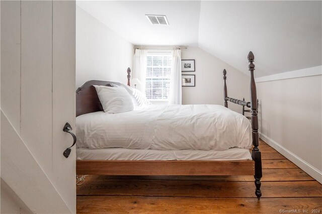 bedroom with vaulted ceiling and hardwood / wood-style flooring