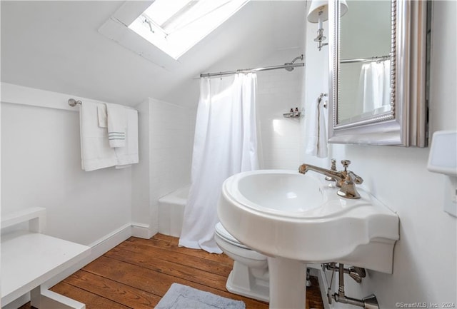 bathroom with shower / tub combo with curtain, wood-type flooring, toilet, and vaulted ceiling with skylight