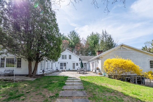 rear view of house featuring a lawn and a patio