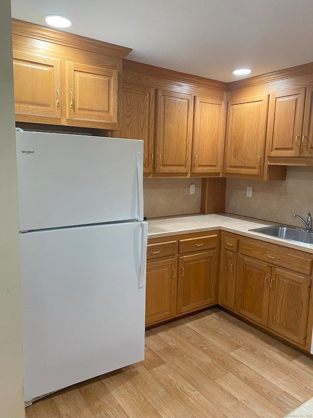 kitchen with light hardwood / wood-style flooring, white refrigerator, and sink