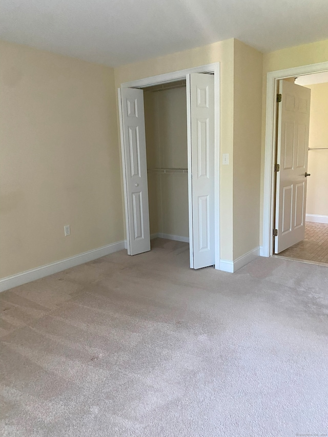 unfurnished bedroom featuring light colored carpet and a closet