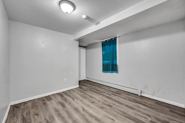 spare room featuring a baseboard heating unit and light wood-type flooring