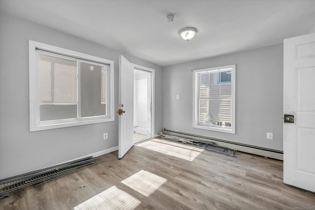 empty room with baseboard heating and light hardwood / wood-style floors