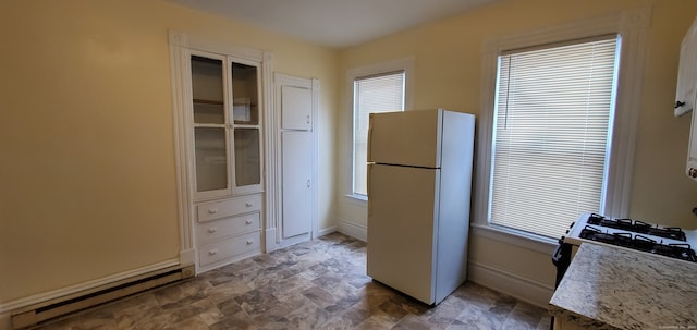 kitchen with plenty of natural light, a baseboard radiator, light stone countertops, and white fridge