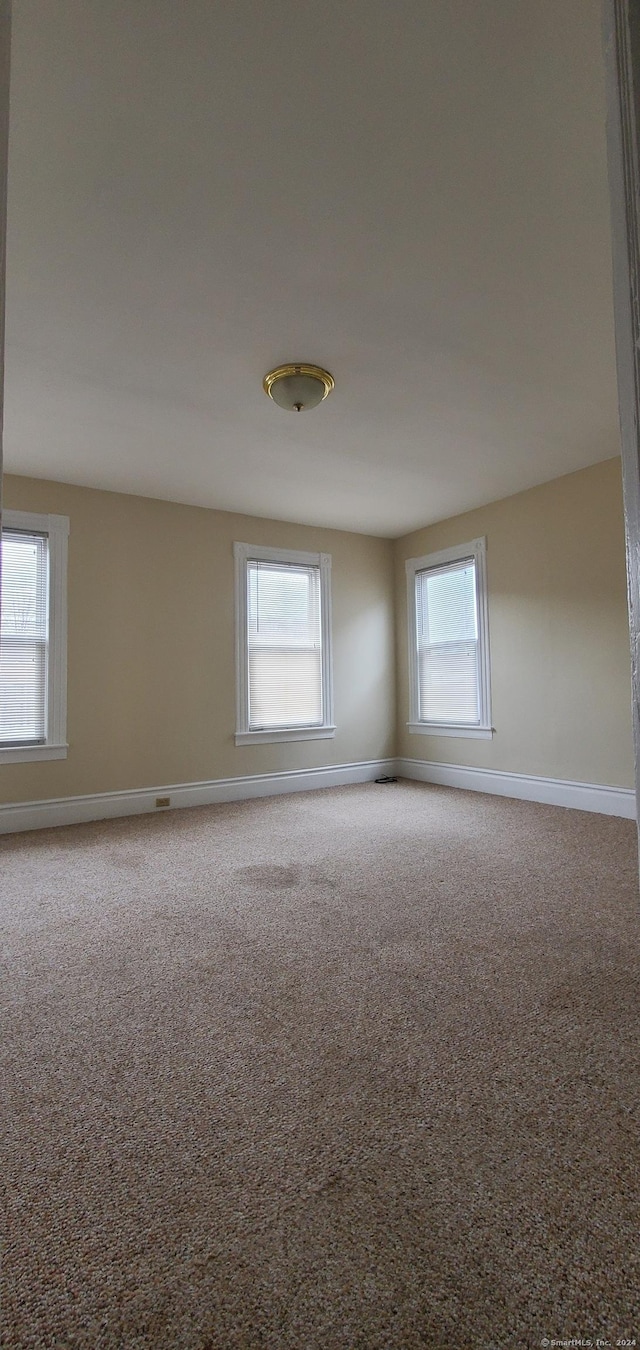 carpeted spare room featuring baseboards