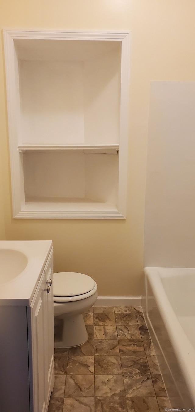 bathroom with a tub to relax in, vanity, and toilet