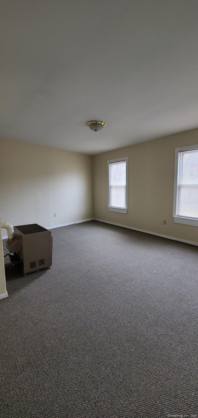 unfurnished room featuring dark colored carpet and baseboards