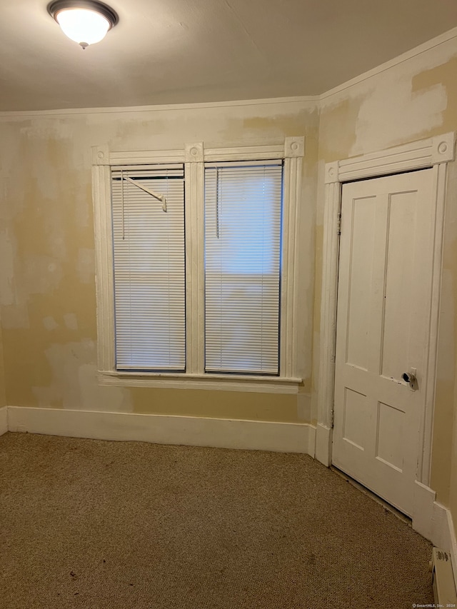 empty room with ornamental molding and carpet floors