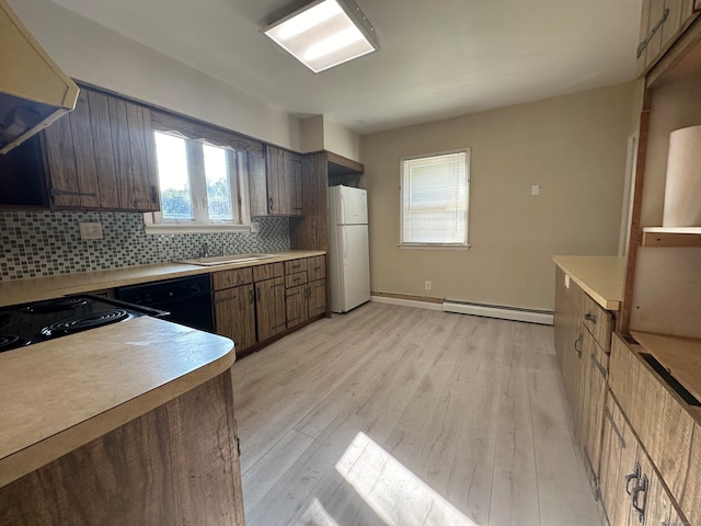 kitchen featuring light wood-type flooring, white fridge, baseboard heating, decorative backsplash, and black dishwasher