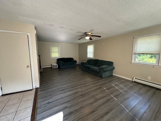 interior space with dark wood-type flooring, ceiling fan, baseboard heating, and a textured ceiling