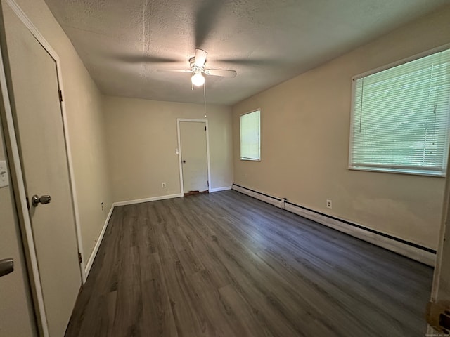 empty room with a baseboard heating unit, dark wood-type flooring, a textured ceiling, and ceiling fan