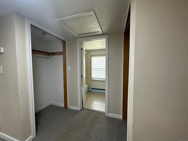 hallway with a baseboard heating unit, tile patterned floors, and a textured ceiling