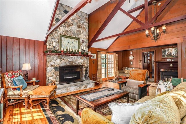 living room with hardwood / wood-style floors, wooden walls, beam ceiling, and a fireplace