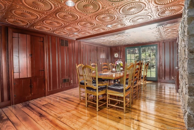 dining space featuring light wood-type flooring and wooden walls