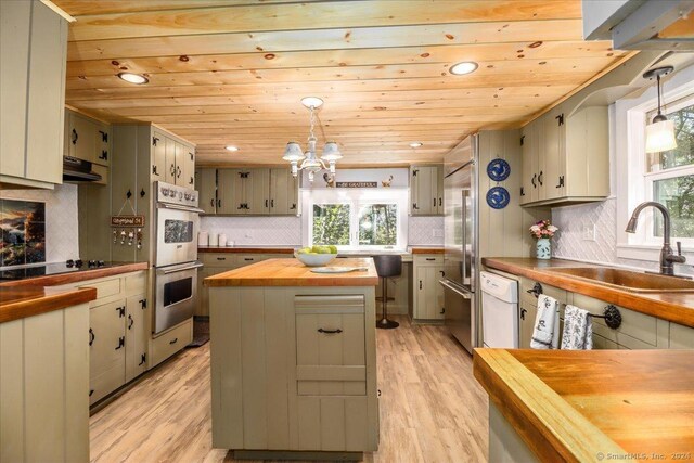 kitchen featuring plenty of natural light, butcher block countertops, and hanging light fixtures