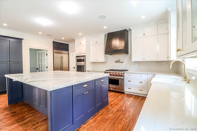 kitchen with high end appliances, white cabinetry, sink, and custom exhaust hood