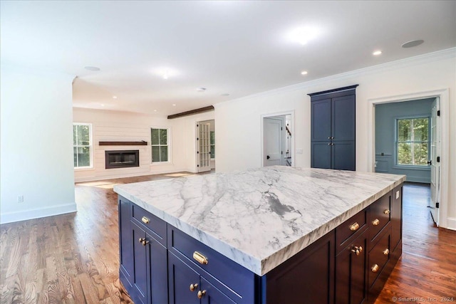 kitchen with dark hardwood / wood-style floors, a center island, ornamental molding, and blue cabinetry