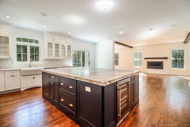 kitchen with a center island, dark hardwood / wood-style floors, white cabinetry, and beverage cooler