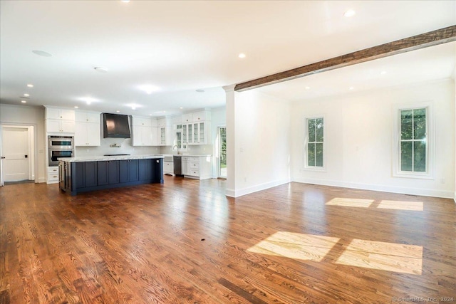 unfurnished living room featuring dark hardwood / wood-style floors, beam ceiling, and sink