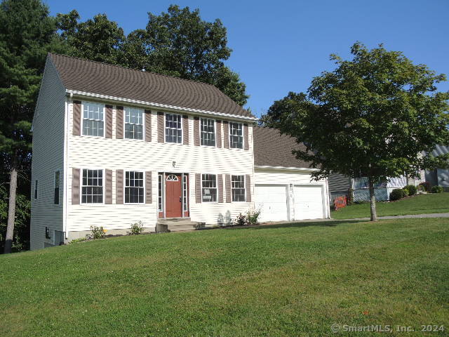 colonial house with cooling unit, a front yard, and a garage