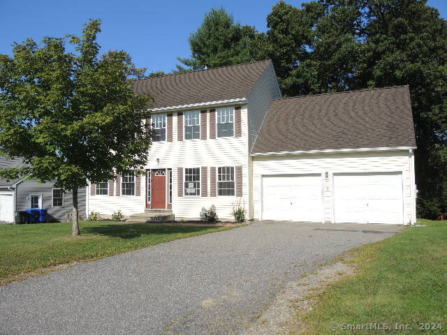 colonial-style house featuring a garage and a front yard