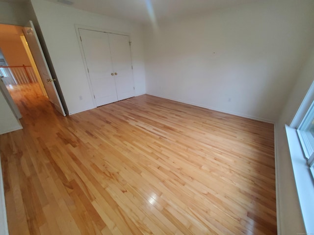 unfurnished bedroom with a closet and light wood-type flooring