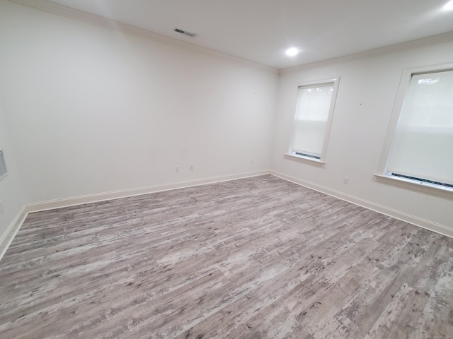 empty room featuring wood-type flooring, crown molding, and a healthy amount of sunlight