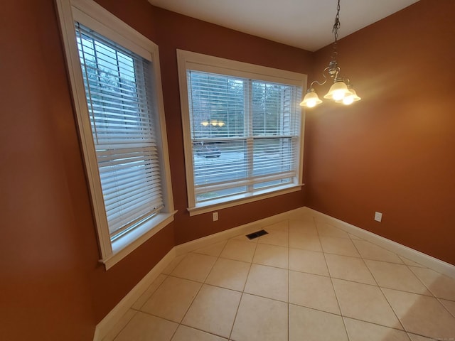 unfurnished dining area featuring light tile patterned flooring and an inviting chandelier