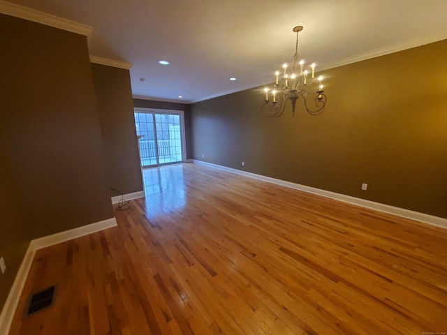 spare room with wood-type flooring, ornamental molding, and a notable chandelier