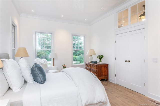 bedroom with ornamental molding and light hardwood / wood-style flooring