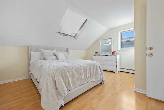 bedroom with lofted ceiling with skylight, a baseboard radiator, and light wood-type flooring