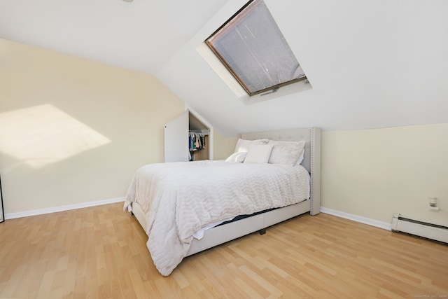 bedroom featuring vaulted ceiling with skylight and hardwood / wood-style flooring