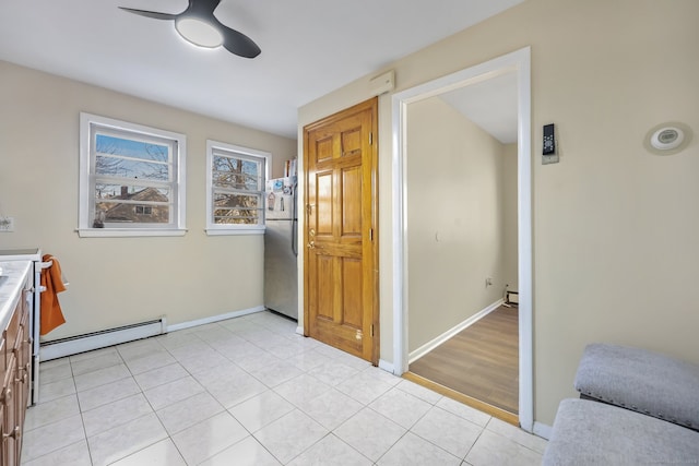 interior space with ceiling fan, light hardwood / wood-style floors, stainless steel refrigerator, and a baseboard heating unit