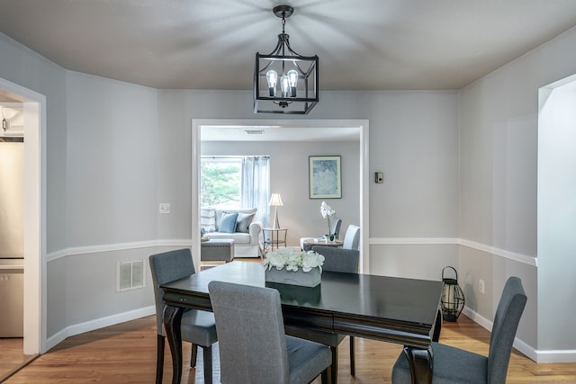 dining area with hardwood / wood-style floors and a notable chandelier