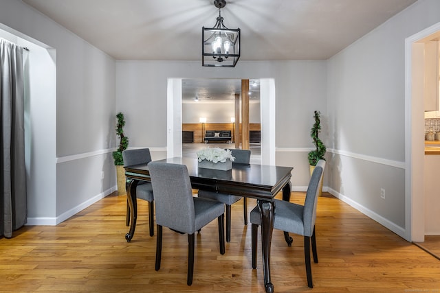 dining space with light hardwood / wood-style floors and a notable chandelier