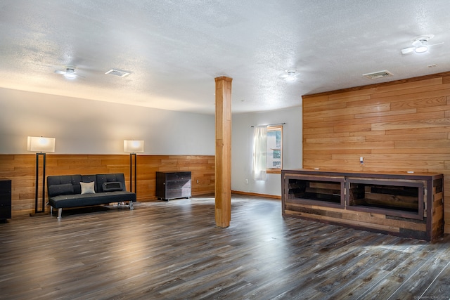 living room with a textured ceiling, wooden walls, and dark wood-type flooring