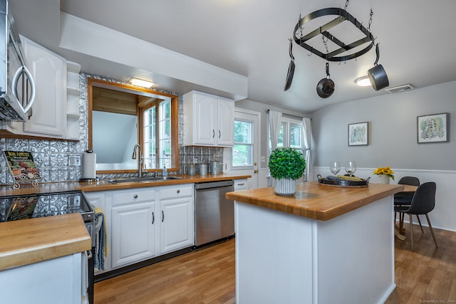 kitchen featuring white cabinets, appliances with stainless steel finishes, and butcher block countertops