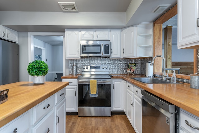 kitchen with stainless steel appliances, light wood-type flooring, sink, and white cabinetry