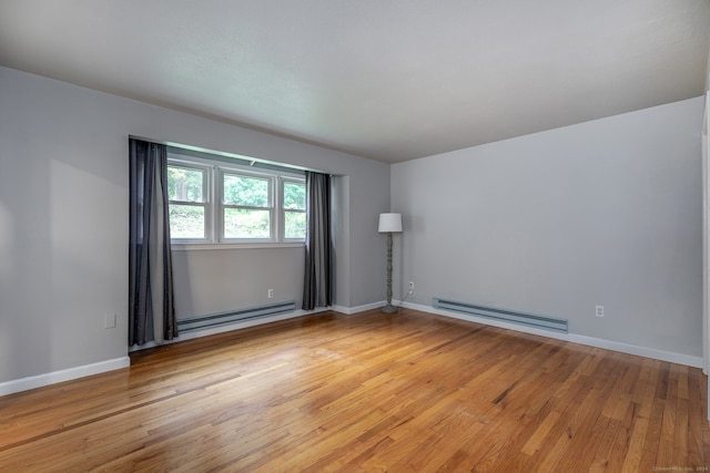 empty room featuring light hardwood / wood-style floors and a baseboard heating unit