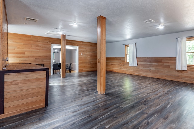 interior space with a textured ceiling, wooden walls, and dark hardwood / wood-style floors