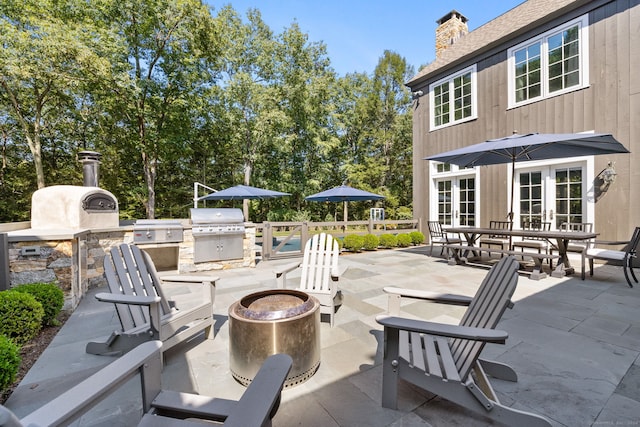 view of patio / terrace featuring french doors, a fire pit, an outdoor kitchen, and area for grilling