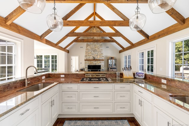 kitchen featuring hanging light fixtures, dark stone countertops, sink, and white cabinets