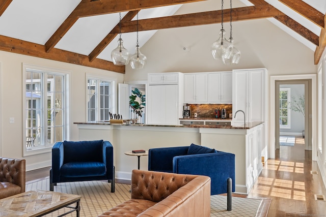 living room with a notable chandelier, beam ceiling, and plenty of natural light