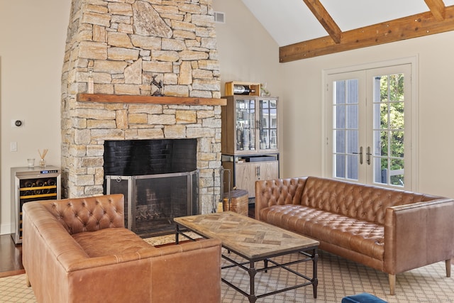 living room featuring beamed ceiling, beverage cooler, high vaulted ceiling, a stone fireplace, and french doors