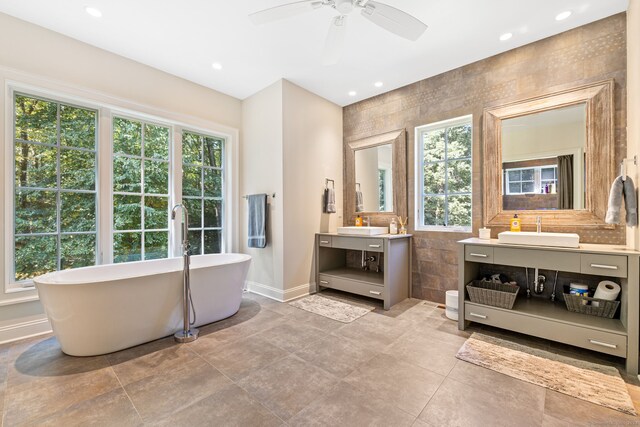 bathroom featuring ceiling fan, vanity, a bath, and a healthy amount of sunlight