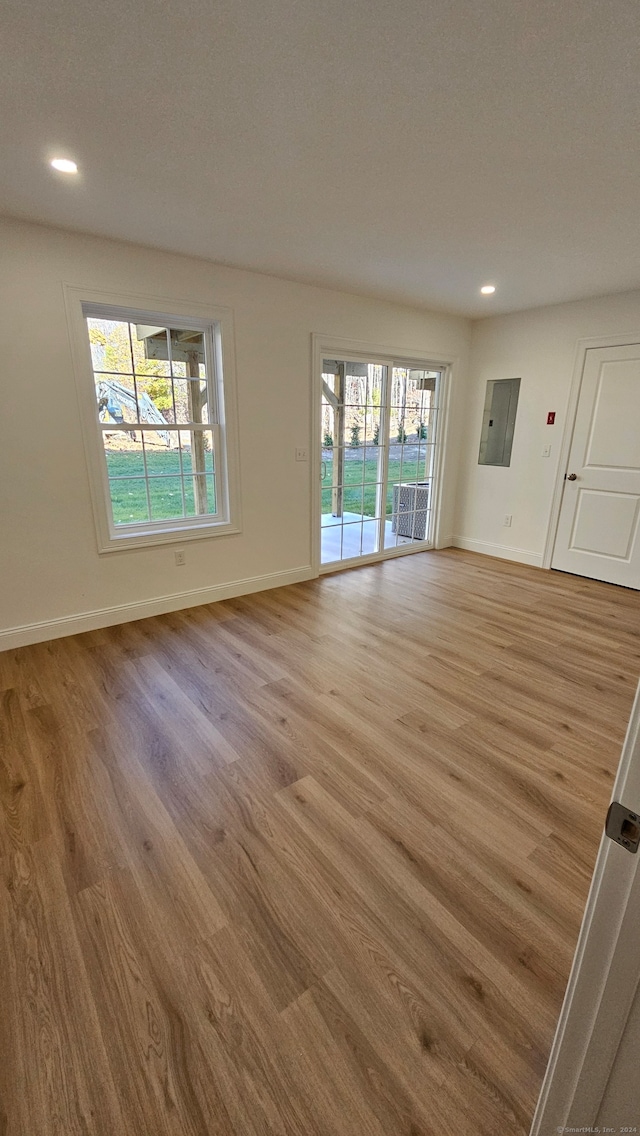 empty room with electric panel, a textured ceiling, and light hardwood / wood-style floors