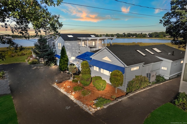 view of front of property with ac unit and a water view