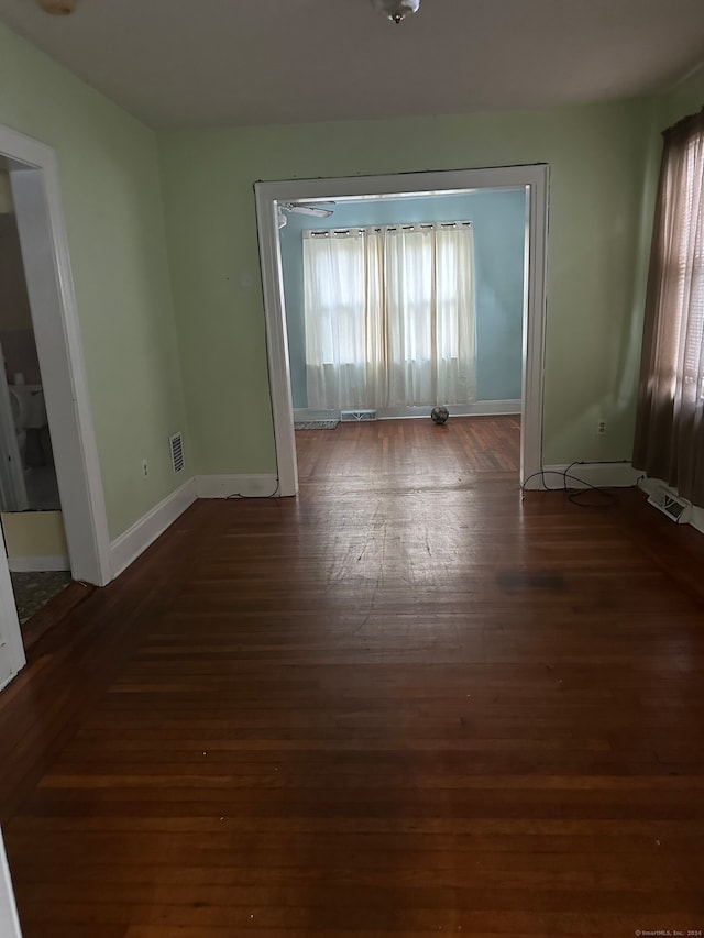 empty room featuring a healthy amount of sunlight and dark hardwood / wood-style flooring