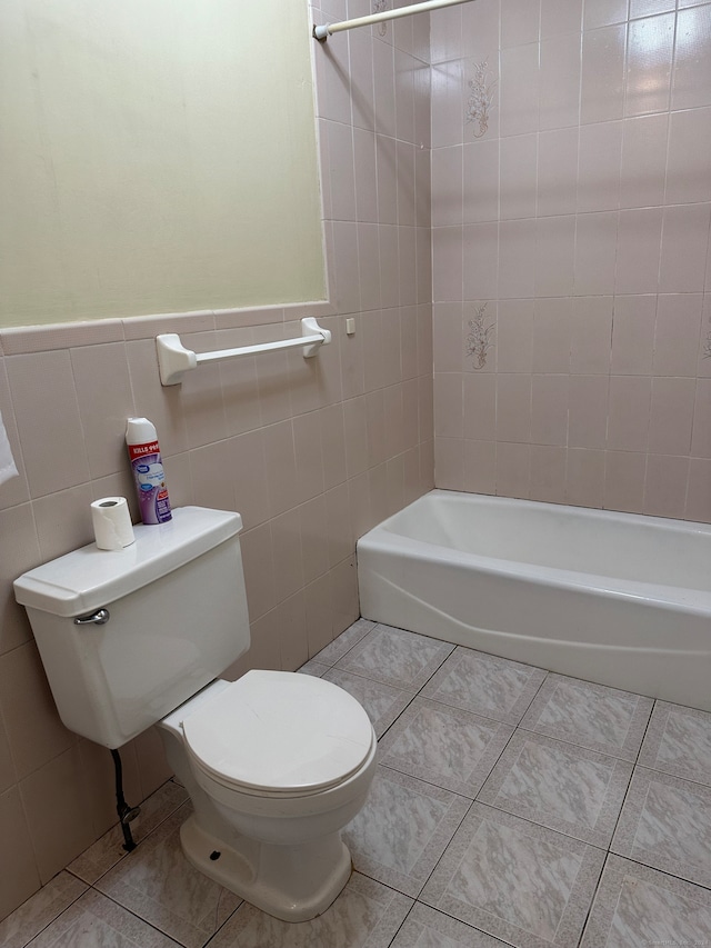 bathroom with tiled shower / bath combo, tile walls, toilet, and tile patterned flooring