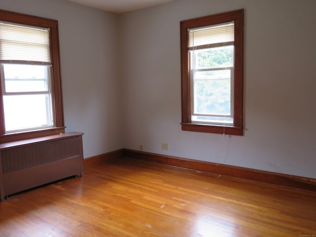 unfurnished room with radiator and light hardwood / wood-style flooring